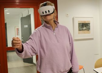 Kvinna i rosa tröja har på sig VR-glasögon som simulerar demenssjukdom