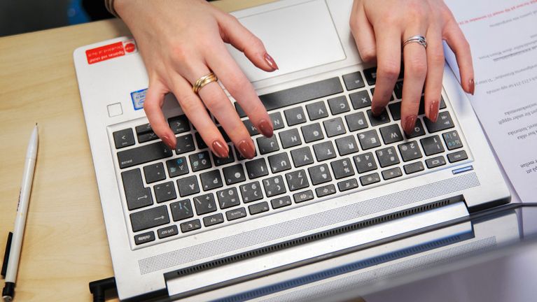 Ett foto av händer som skriver på en laptop.
