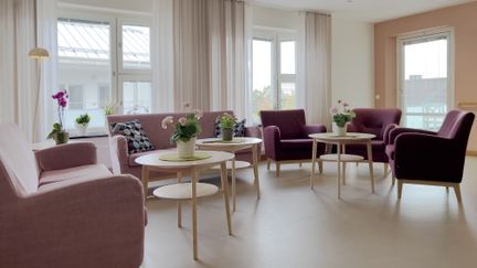 Aktivitetsrum med flera fåtöljer och soffor. Rummet har ljusa väggar och golv.