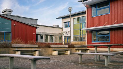 En skolgård med bänkar förgrunden och skolbyggnaden i bakgrunden