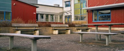 En skolgård med bänkar förgrunden och skolbyggnaden i bakgrunden