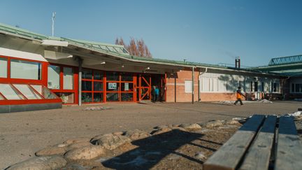 Lillebyskolans skolgård med några personer och en bänk i bakgrunden.