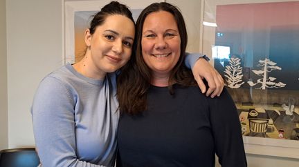 Två personer håller om varandra och tittar in i kameran.