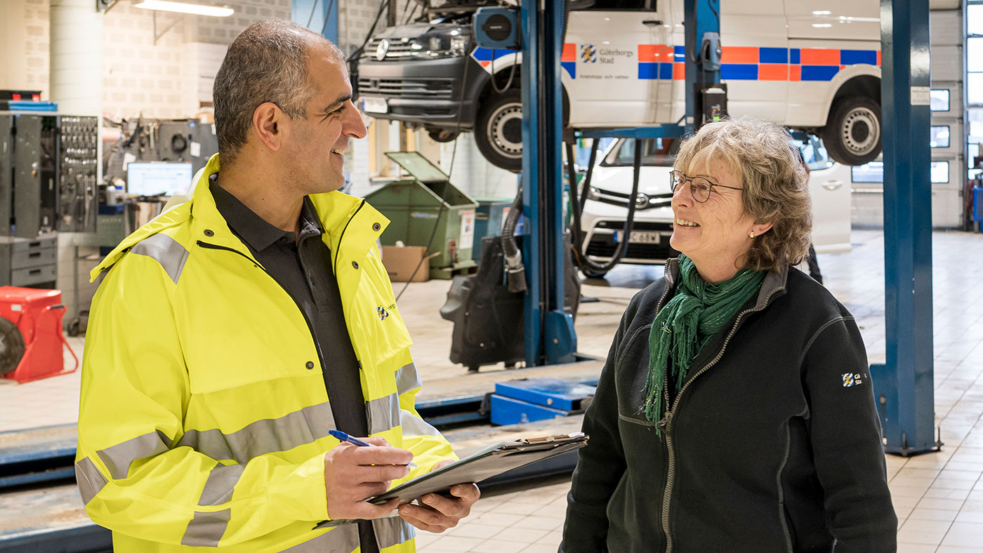 En man och en kvinna står bredvid varandra i en verkstad. De pratar och skrattar.