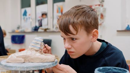 En deltagare i Kulturskolan som koncentrerat målar sin sfinx av keramik. 