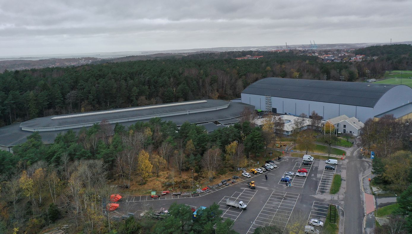 Flygbild över idrottsområde med kringliggande natur och skog.