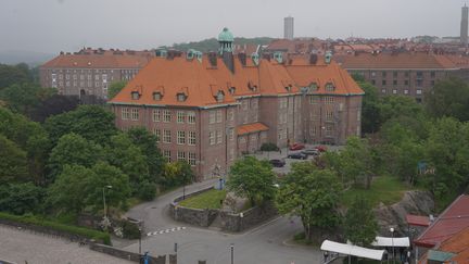 En röd tegelbyggnad i fyra våningar med ett rött tegeltak.