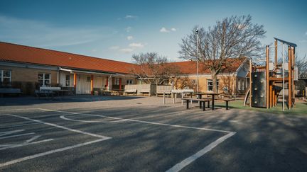 En tom skolgård med en lekställning och bänkar.