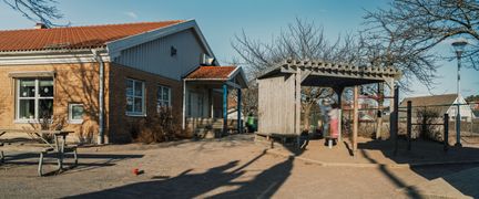 Två elever som leker på en balansplint i en sandlåda på en skolgård.