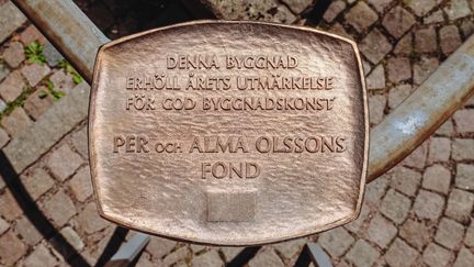 Bild på plaketten som Per och Alma Olssons fond delar ut till årets byggnad.