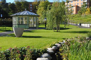 En glaspaviljong i en grön trädgård