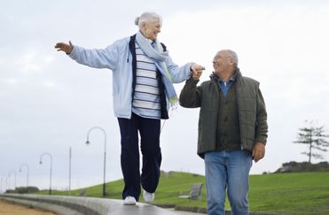 En person balanserar på en mur, den andre håller hennes hand.