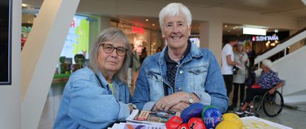 Två kvinnor i jeansjacka ler in i kameran