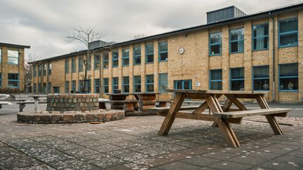 Ett picknickbord framför Brunnsboskolan med några skolbyggnader i bakgrunden.