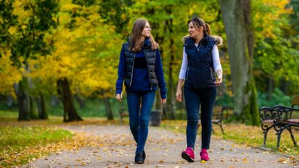 Två personer går i en park och pratar med varandra.