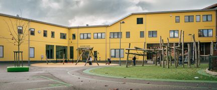 Entré till Gamlestadsskolan med en lekplats och skolgård i bakgrunden.