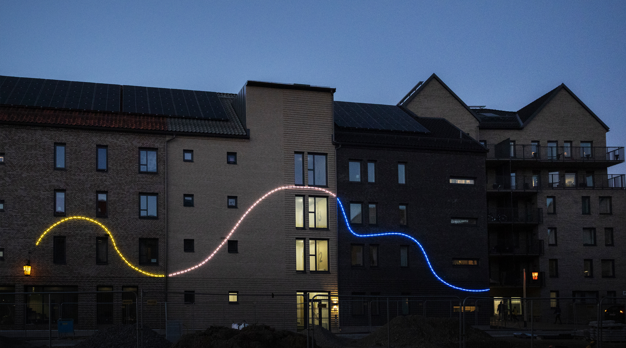 Ett hyreshus med en ljusslinga i flera färger som slingrar sig längs fasaden