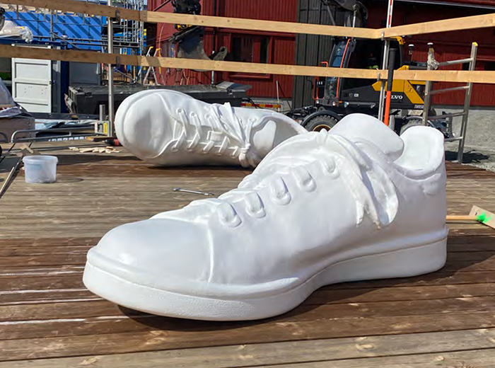 Tv&aring; skulpturer av j&auml;ttestora vita sneakers, varav en ligger sl&auml;ngd p&aring; sidan