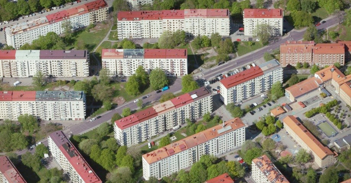 En flygbild över stadsdelen Johanneberg, där vita hus, grönskande träd och bilvägar syns. 