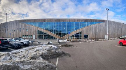 Kvibergs is- och sporthall från utsidan, med en parkering i förgrunden