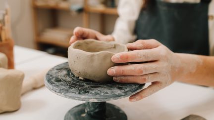 En person gör en skål i lera.