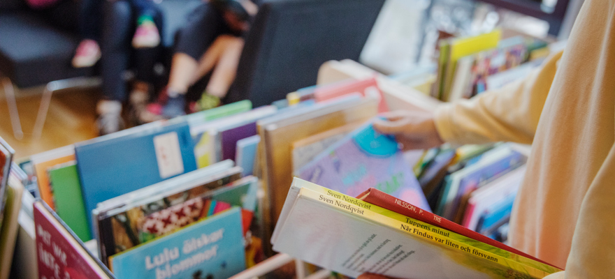 Person bläddrar i en boklåda på biblioteket