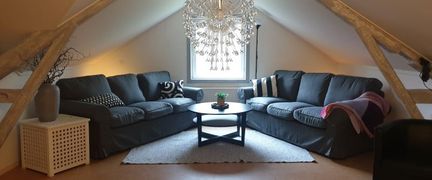 En övervåning med snedtak och två stora soffor i vinkel.