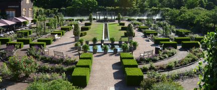 Rosplanteringar i flera, ovala, rader med gångar emellan.