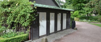 Brun byggnad i trä med fyra vita dörrar.