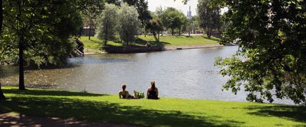 Två personer sitter på gräsmattan intill vattnet.