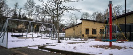Olshammarsskolans lekplats med ett par gungor och en klätterställning i fokus.