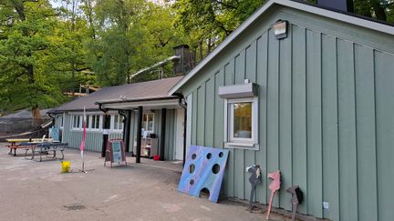 Ett grönt hus med en leksaker framför huset