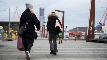 Ett foto av två personer som promenerar bort ifrån kameran över en öppen plats.