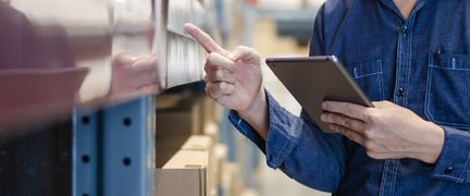 En han pekar på en hylla i en lagerlokal.