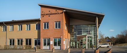 En skolbyggnad i gult och orange tegel och en stor glasad entré