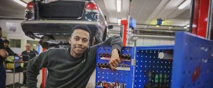 En person som lutar sig mot ett skåp i en bilverkstad.
