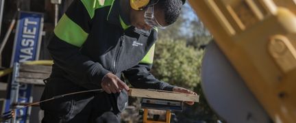 En person som mäter en träbit med en tumstock.