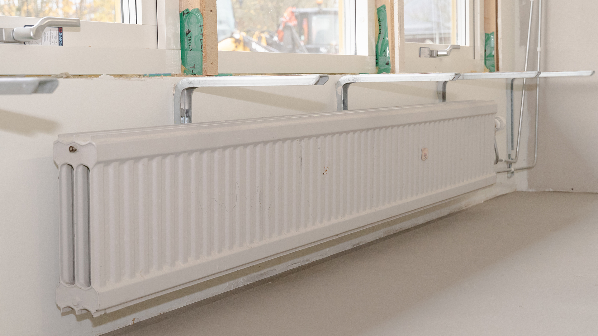 Ett l&aring;gt element str&auml;cker sig l&auml;ngs v&auml;ggen under h&ouml;ga f&ouml;nster. Hyllkonsoler sticker ut mellan elementet och f&ouml;nstren.