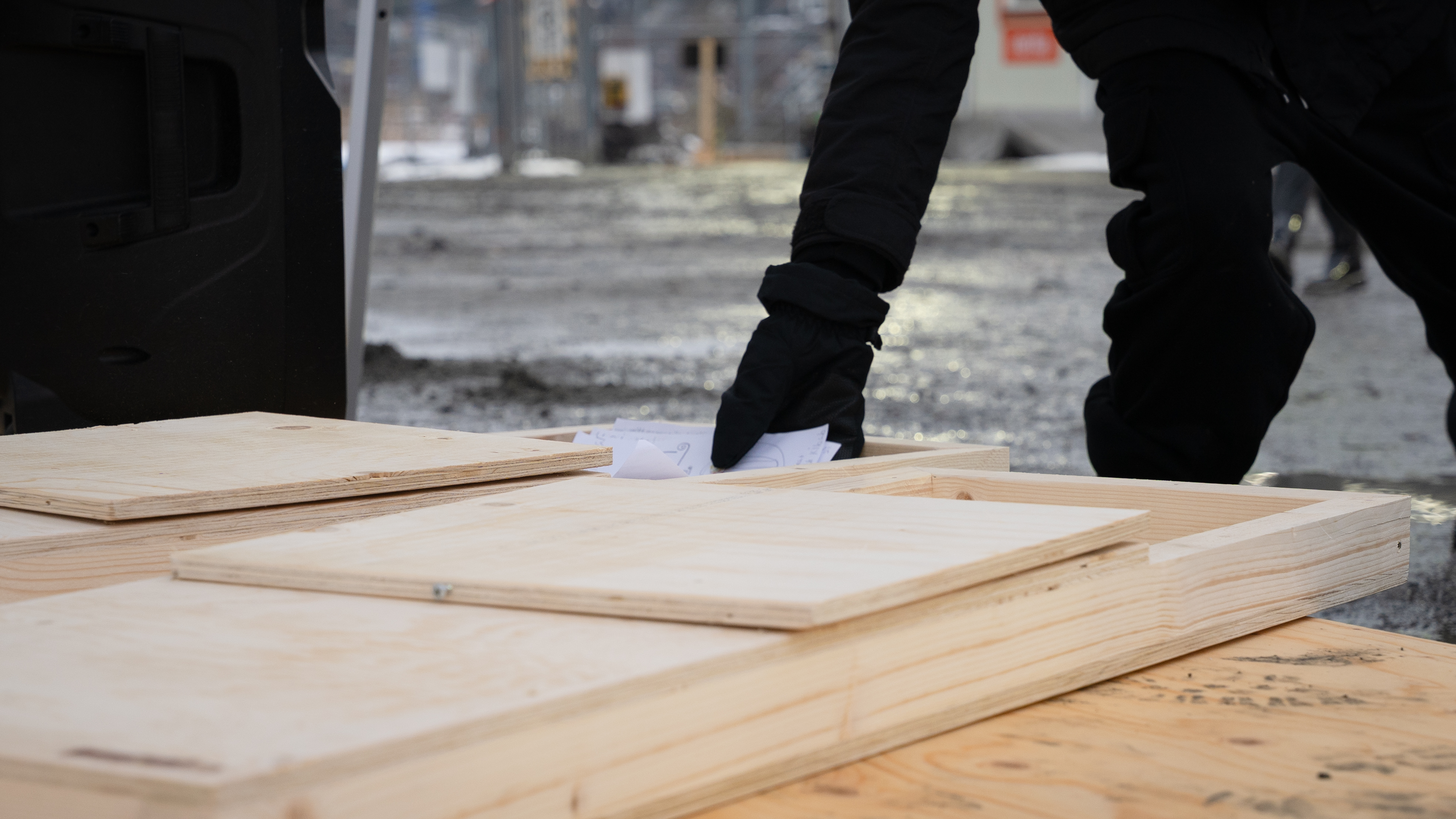 En vantbekl&auml;dd hand l&auml;gger ner en bunt papper i en l&aring;ngsmal tr&auml;l&aring;da.