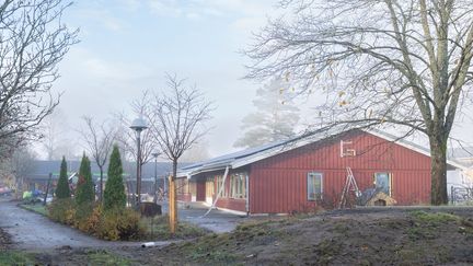 En röd enplansbyggnad med stegar och byggmaterial utanför.