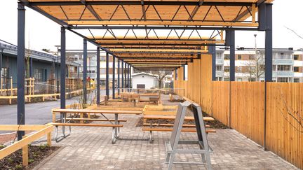 En pergola av stålbalkar och trä.