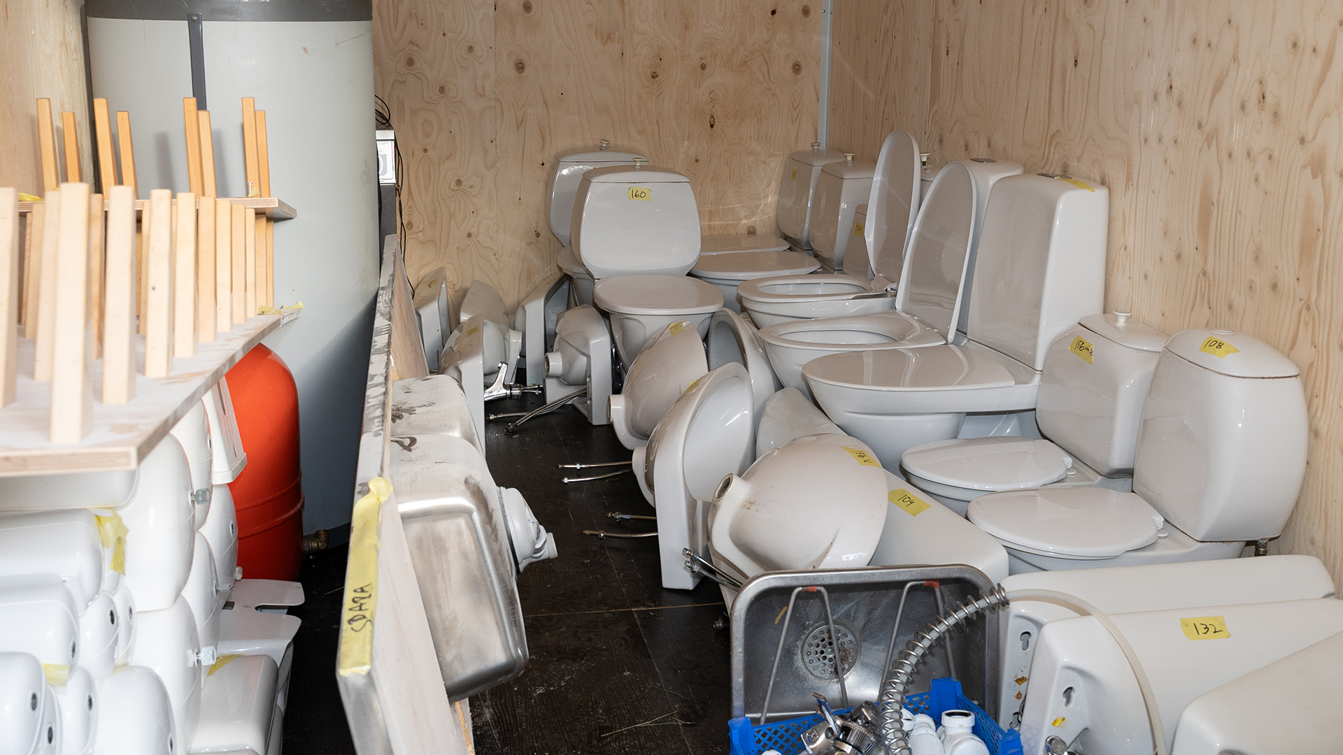 Ett litet utrymme fullt med toalettstolar, radiatorer, hyllor och andra inventarier.