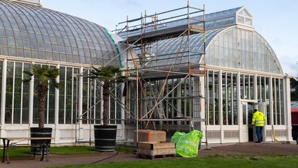 Ett stort glasväxthus med en byggnadsställning utanför.