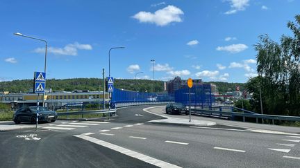 En körbana med gång- och cykelbana till vänster över en motorväg. Skyddsstaket längs vägen där den passerar över ett mot.