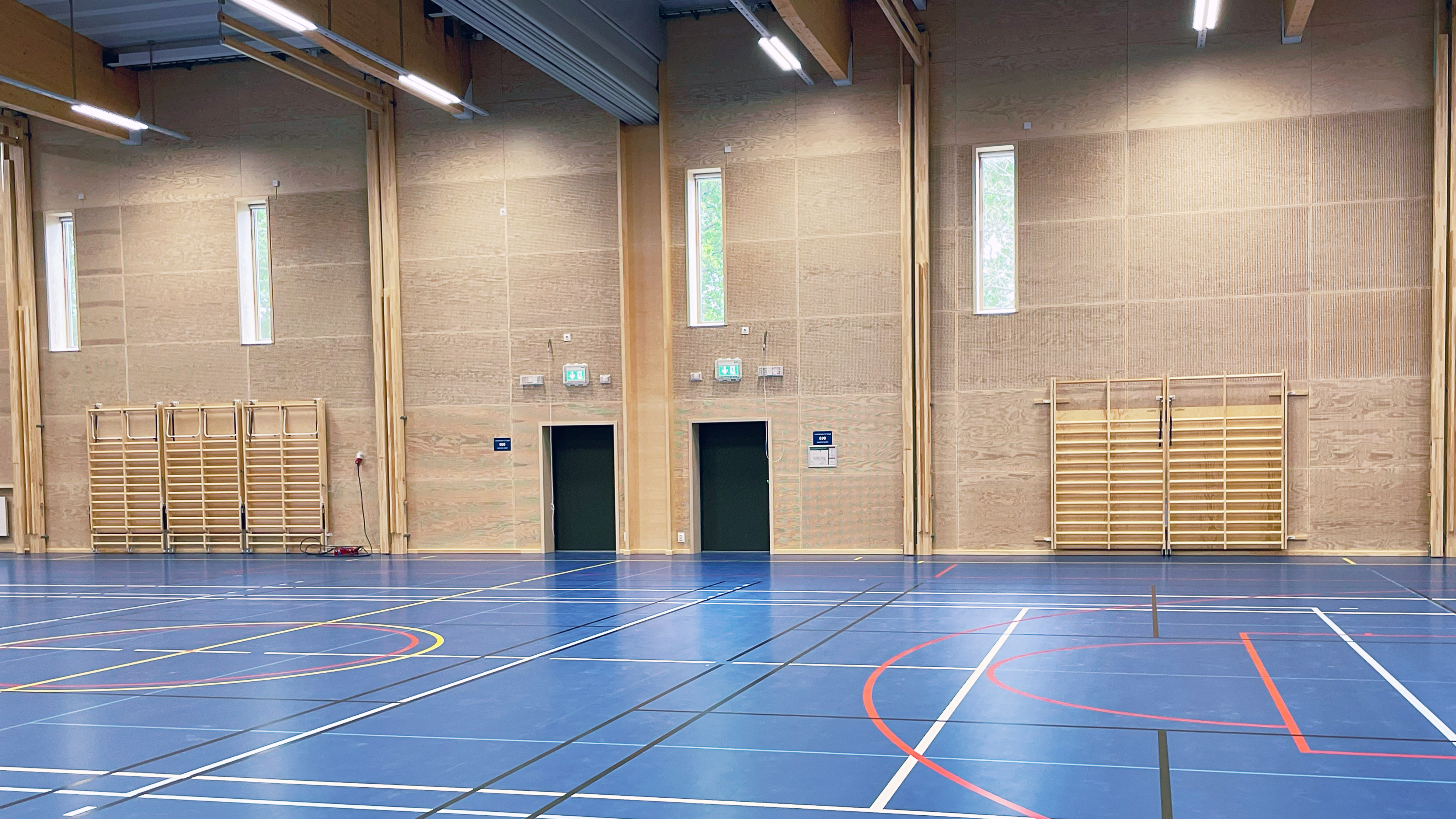 Idrottshall med ribbstolar i tr&auml; och bl&aring;tt golv