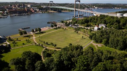 Drönarbild över den stora gräsmattan och strandlinjen mot älven i Färjenäsparken. Över älven syns Älvsborgsbron.