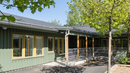 En grön enplansbyggnad i vinkel.