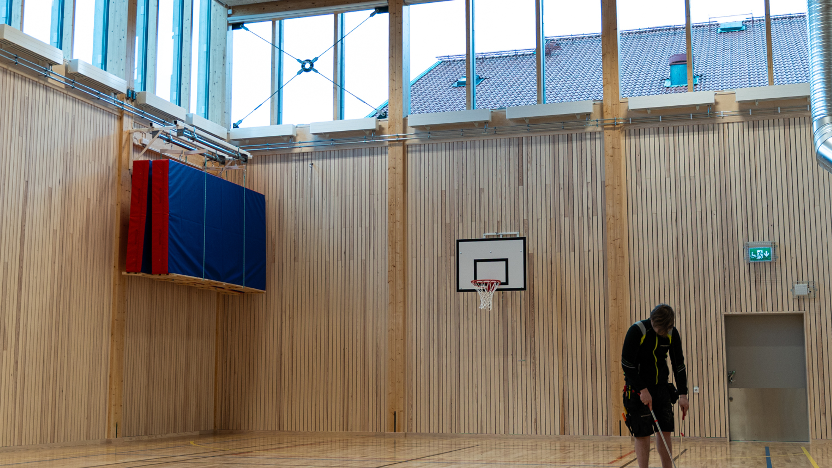 En stor sal med träinredning och en basketkorg på väggen.