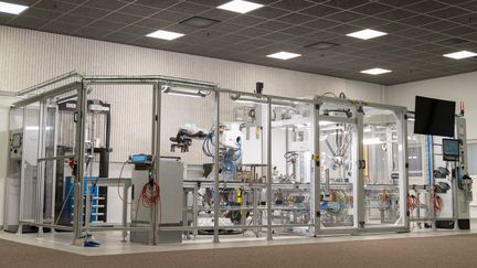 En glasbur med robotar som ska simulera tillverkningen av celler för batterier