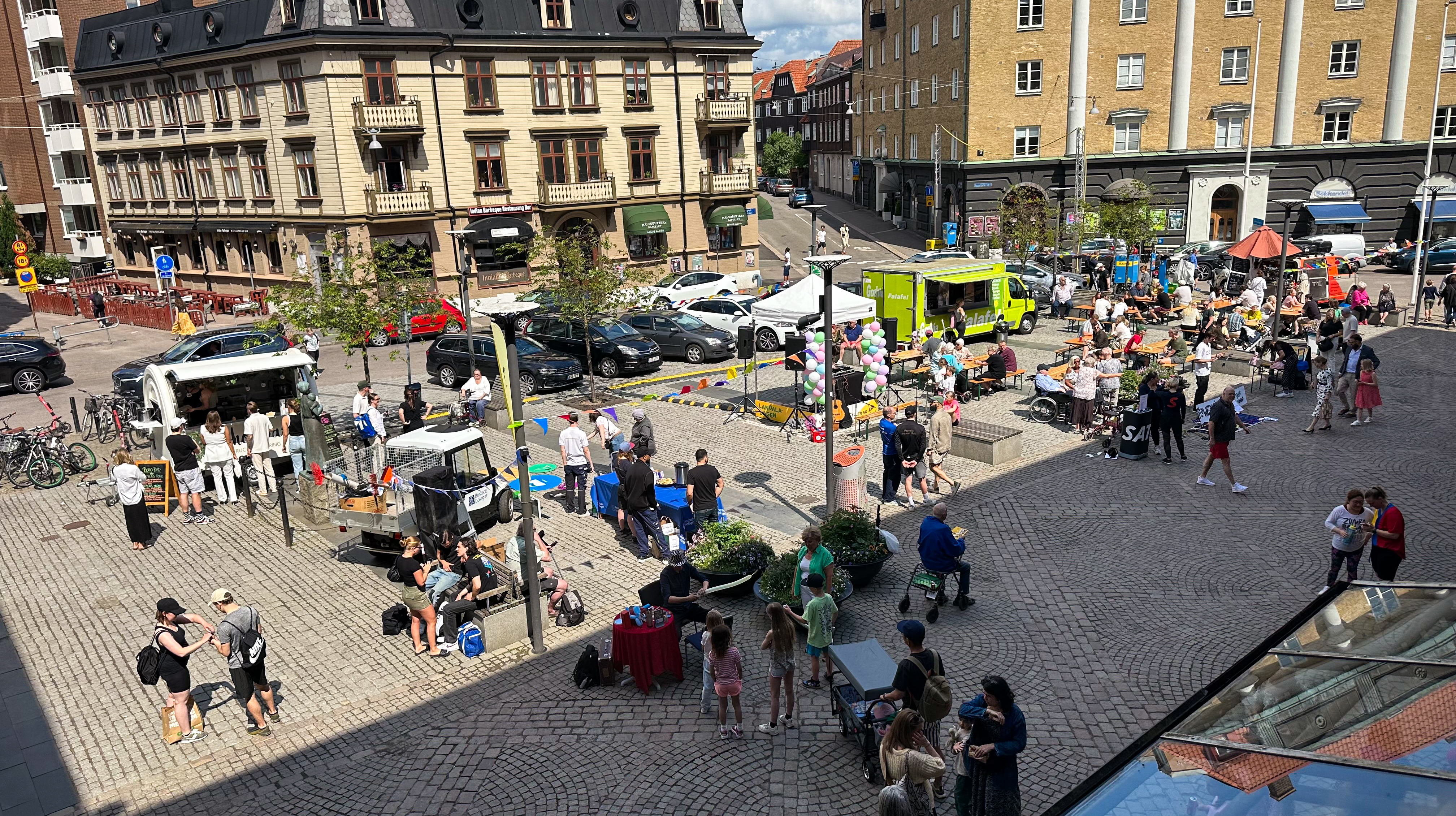 Bilden visar Landala torg med flera personer som deltar i olika aktiviteter på torget